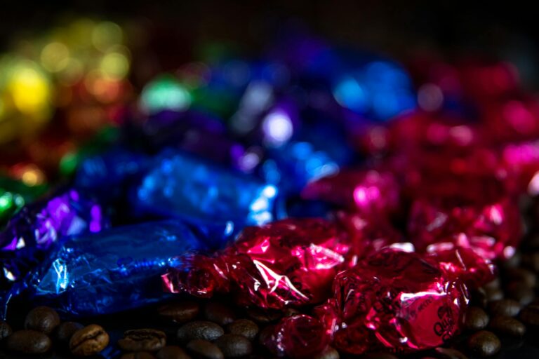 A vibrant assortment of wrapped candies on coffee beans with a blurred bokeh effect.