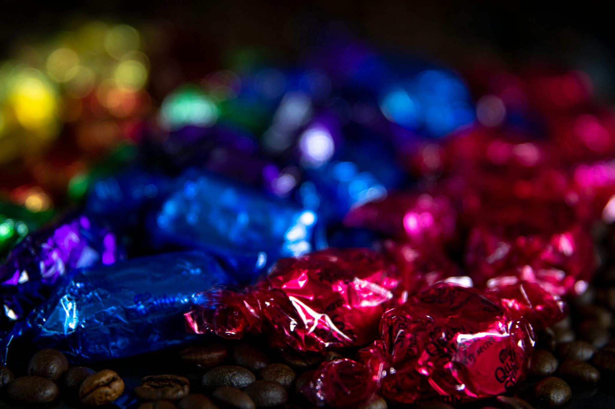 A vibrant assortment of wrapped candies on coffee beans with a blurred bokeh effect.
