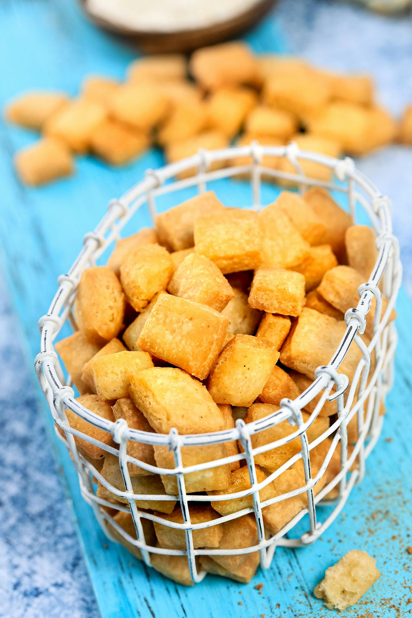 Delicious homemade square cookies in a white basket on a blue surface.